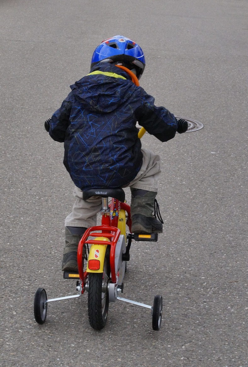 Boy riding bike with training wheels