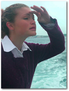 Woman on the ocean, peering into the distance.